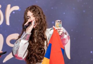 Singer Maléna holds up an Armenian flag on stage.