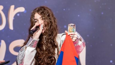 Singer Maléna holds up an Armenian flag on stage.